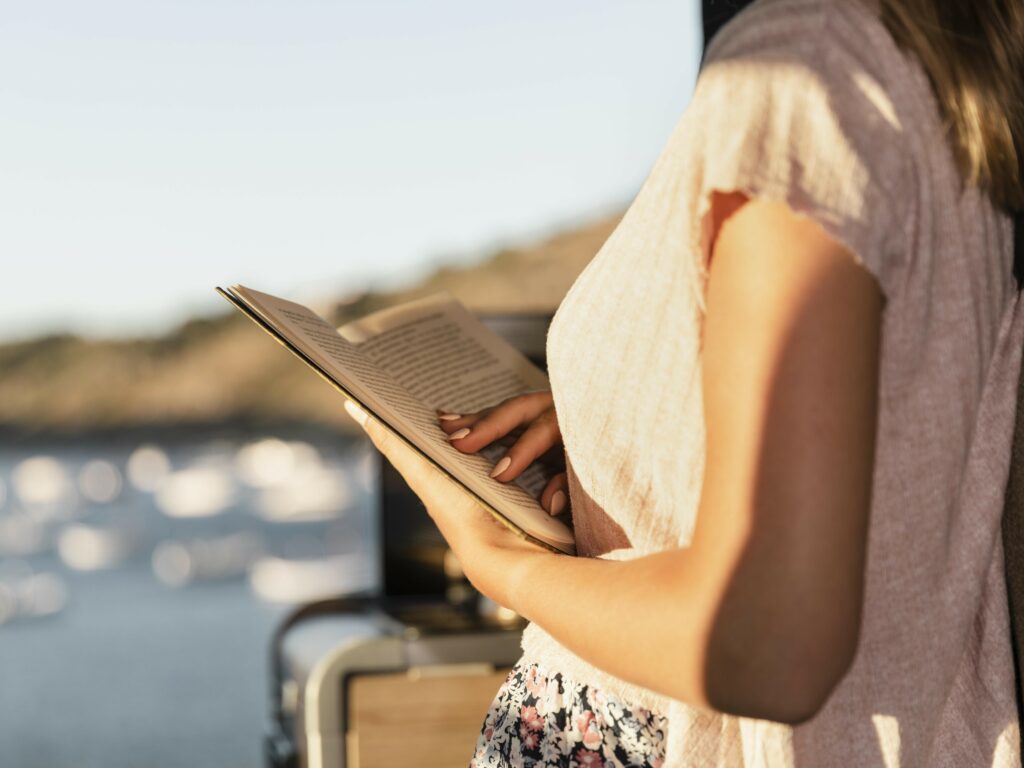 Young beautiful woman reading by lake